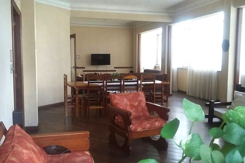 Sala de estar em primeiro plano, de jantar em segundo plano e de TV ao fundo