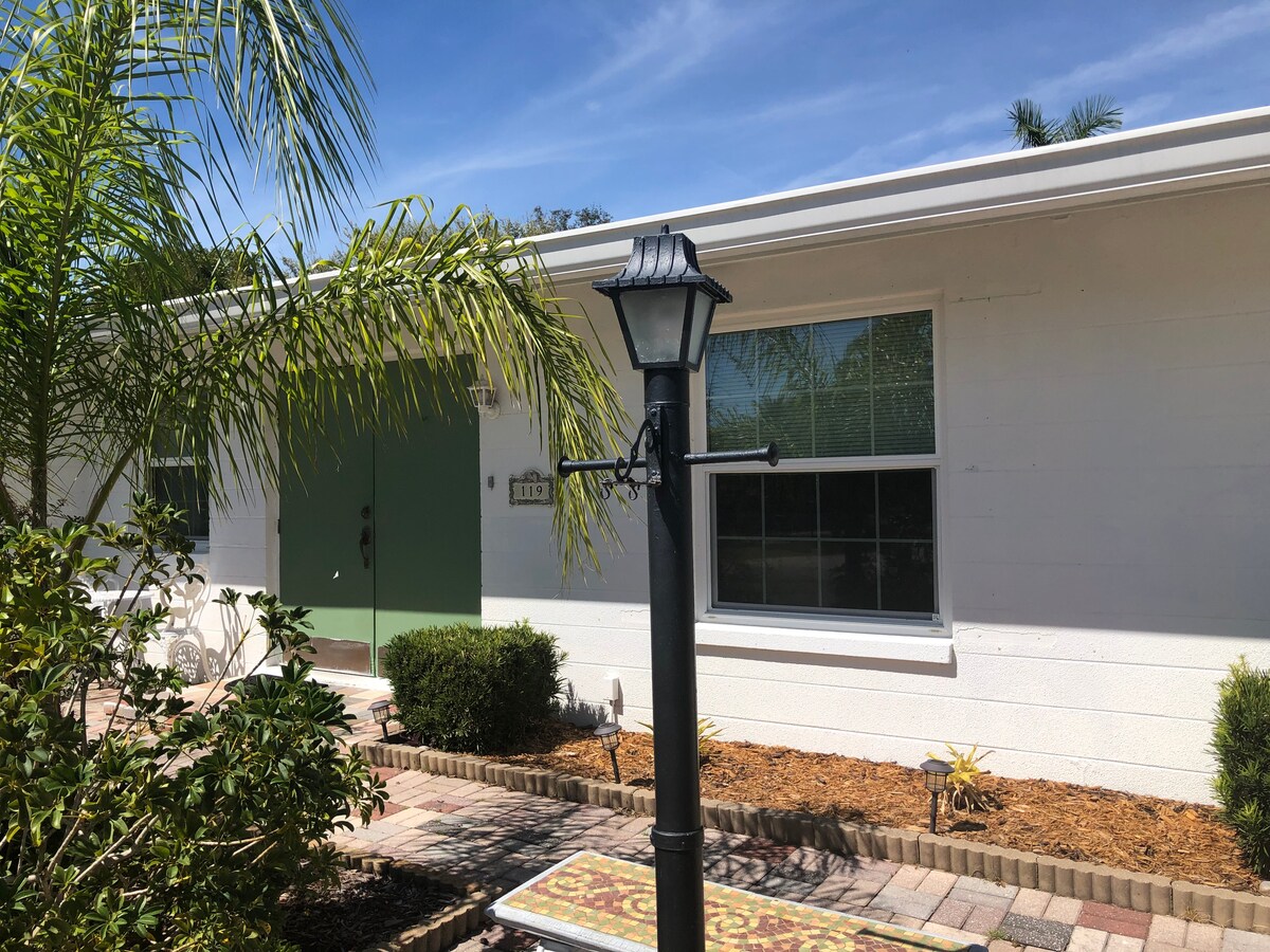 The exterior of the property features a well-maintained front yard with lush greenery and ornamental plants. A decorative lamp post stands near a paved pathway leading to the entrance, which is accented by a large window that invites natural light.