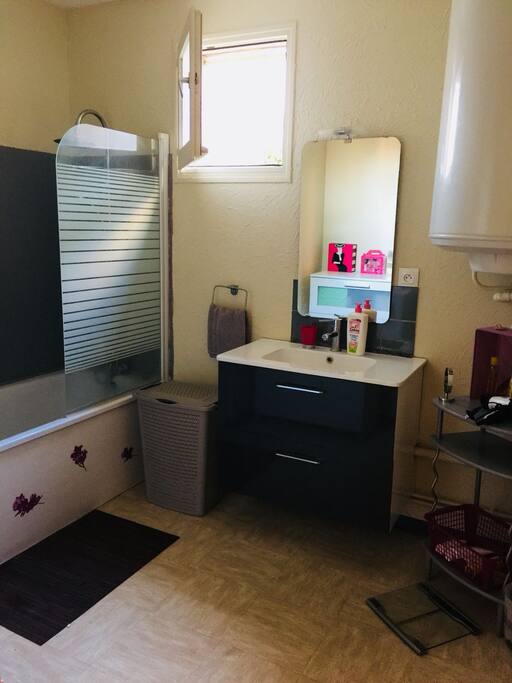 Salle de bain avec baignoire, sèche cheveux à disposition ainsi que des serviettes.