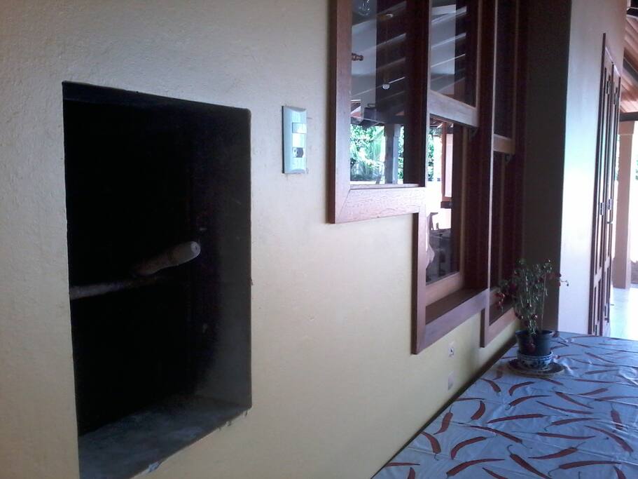 Churrasqueira ao lado da mesa que acomoda confortavelmente 10 pessoas.