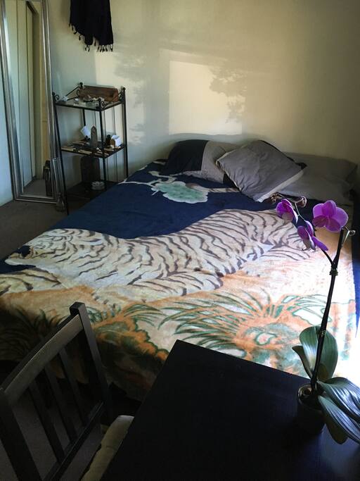 Queen bed, mirror, side table, view from working area.