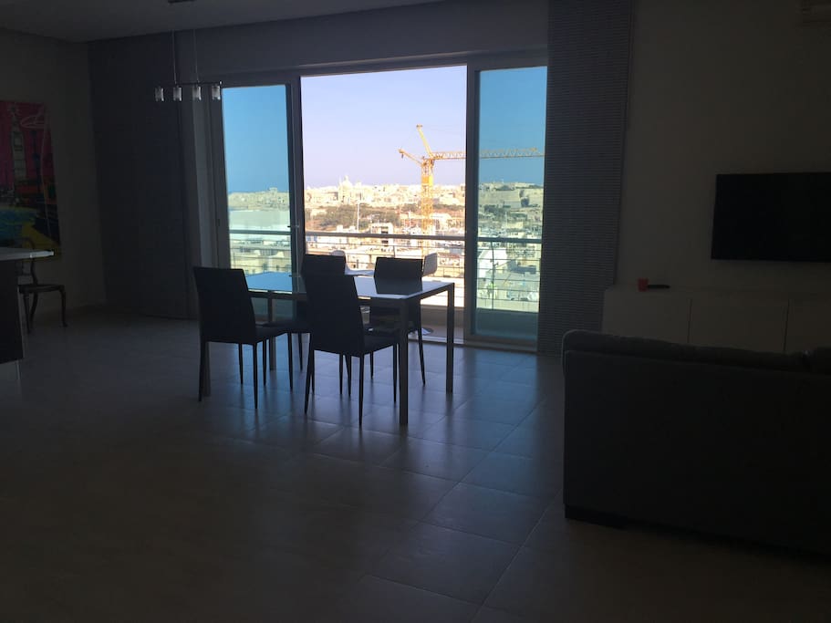 Spacious living dining kitchen area with big terrace doors, balcony and spectacular views on the capital Valletta, 180 degrees over the island and lots of morning light (South facing).