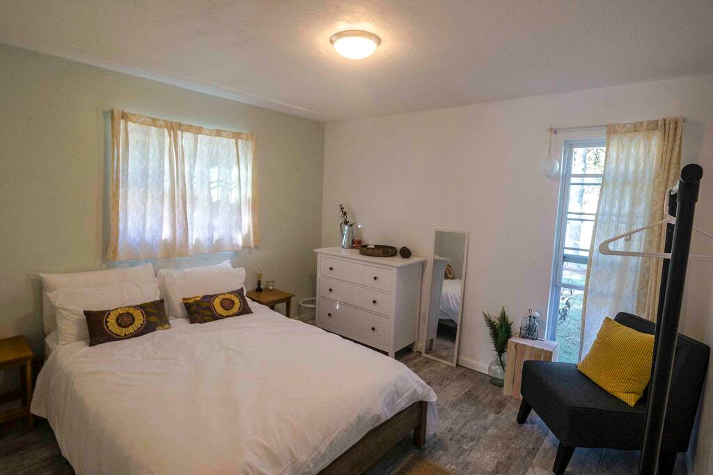 Guest room with queen bed, chair, 3-drawer and hanging rack