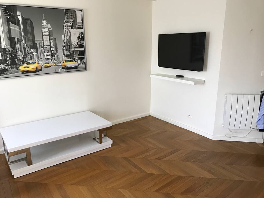 Seconde vue du salon avec écran télévision fixé au mur