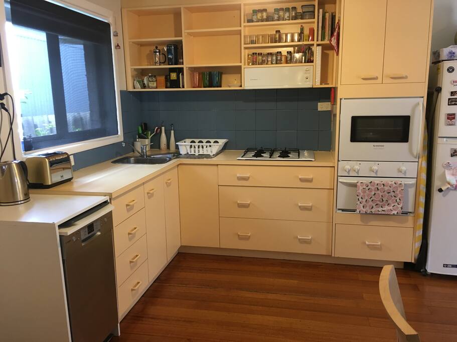 Kitchen with dishwasher, stove top, oven, toaster, kettle, fridge with freezer, all cutlery and crockery