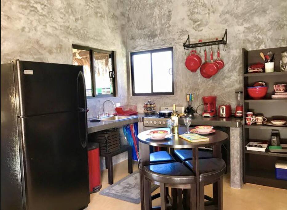 Full kitchen with fridge, oven, microwave, coffee pot, blender, toaster, pots and pans, dishes and spices.