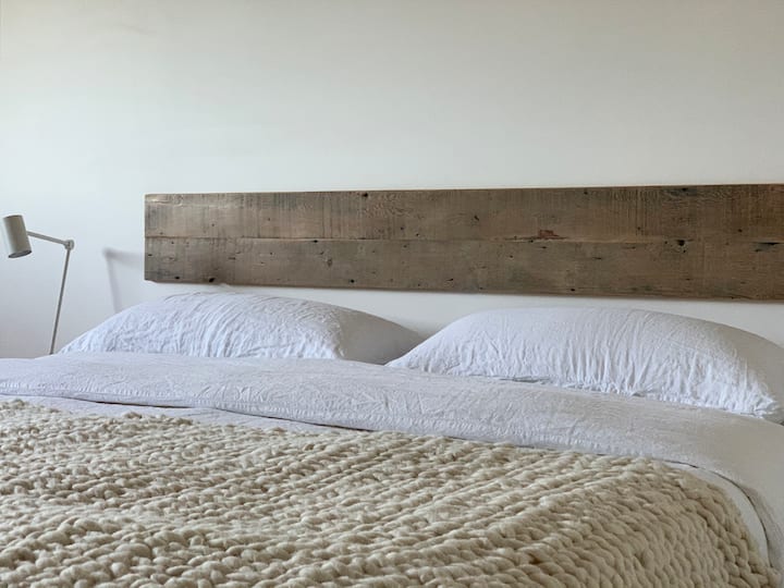 חדר שינה שלישי: מיטת קינג סייז עם כריות קינג סייז, מצעים רכים ודוכני לילה טעינה אלחוטית בכל צד. 