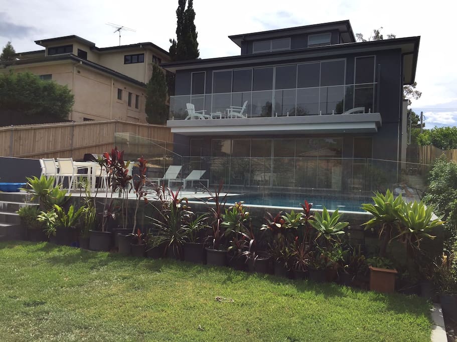 Rear of home showing 2 levels with wide opening sliding doors for natural light, pool, patio and balcony