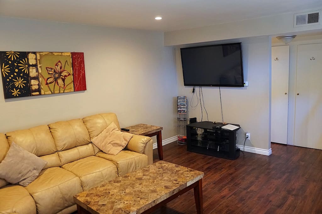 Large Living area with comfy couches, dimmed lighting, hardwood floors and large HDTV