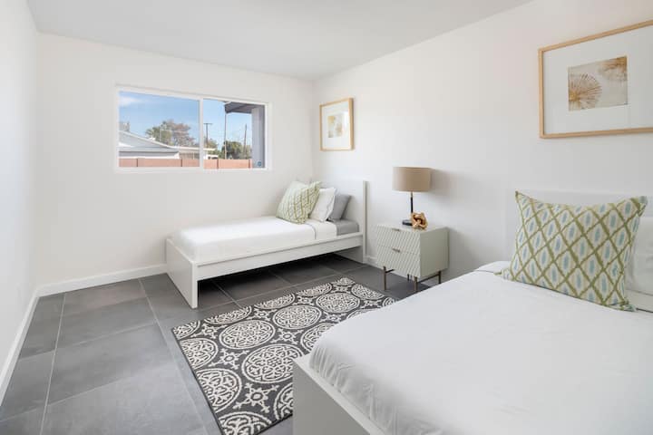 חדר אורחים עם שתי מיטות נפרדות ושולחן כתיבה עם כיסא לכל העבודה מהבית. 