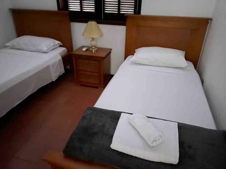 Begane grond slaapkamer met twee eenpersoonsbedden en inbouwkast. Het omvat het gebruik van een handdoekenset (bad en gezicht).