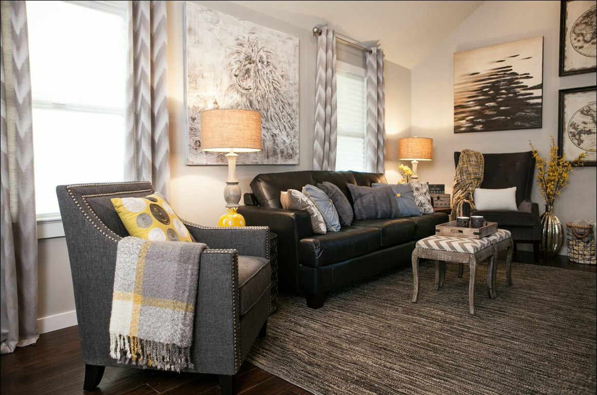 A welcoming living area features a dark leather sofa adorned with plush cushions. An accent chair with a textured fabric sits nearby, complemented by a soft throw. Two lamps illuminate the space, along with a unique coffee table and decorative wall art, enhancing the cozy atmosphere.