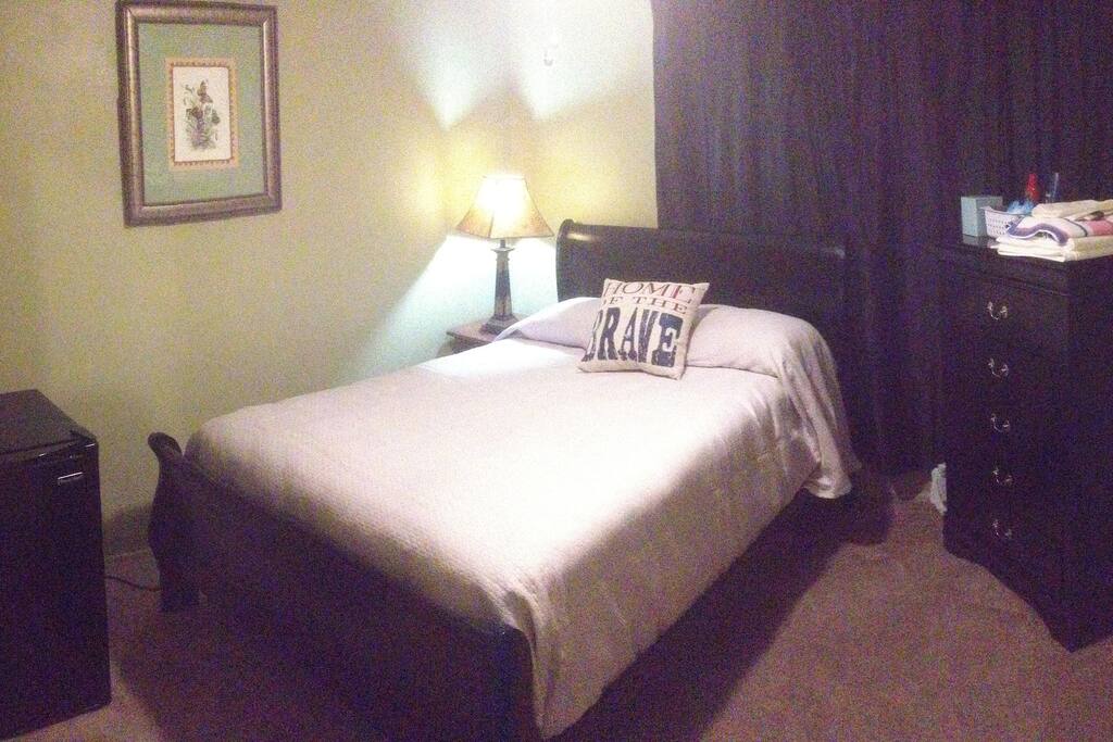 1st Bedroom features ceiling fan, refridgerator, blackout drapery for daytime rest, and relaxing green color paint