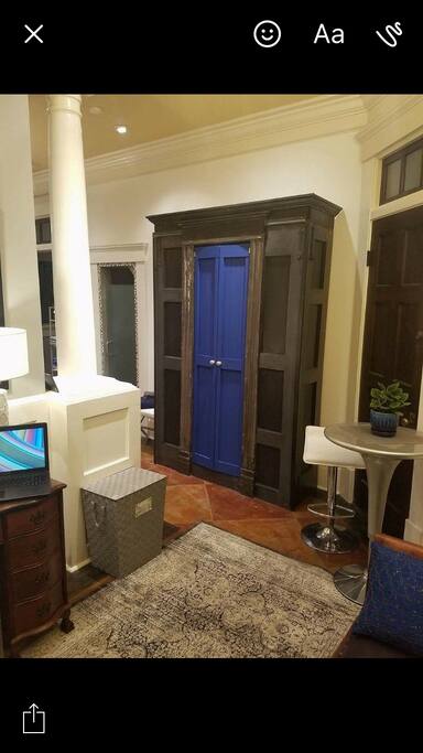 Foyer entrance to carriage house unit with writing desk, antique fireplace mantle and sitting area for eating. Beautiful custom made wardrobe to House your belongings