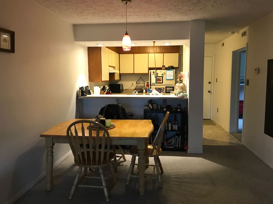 All are welcome in the common area featuring the kitchen, dining table, and sofa.