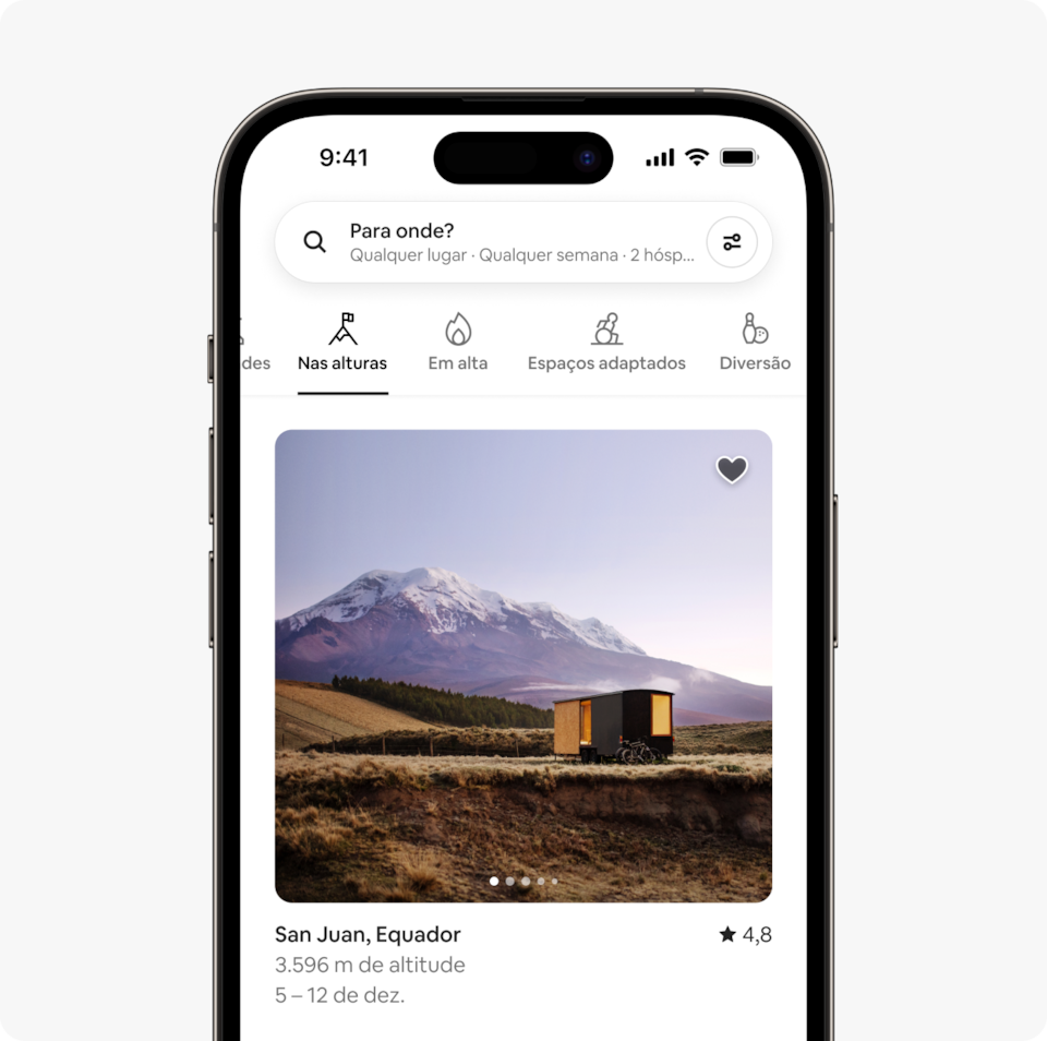 Um laptop e um celular mostram a página inicial do Airbnb com duas linhas de acomodações de uma nova categoria da edição de inverno do Airbnb, chamada "Nas alturas", que apresenta acomodações em grandes altitudes, cerca de 3 mil metros acima do nível do mar.