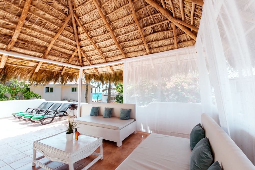 Rooftop terrace: sitting area, dining area, BBQ, sun chairs, partial ocean view