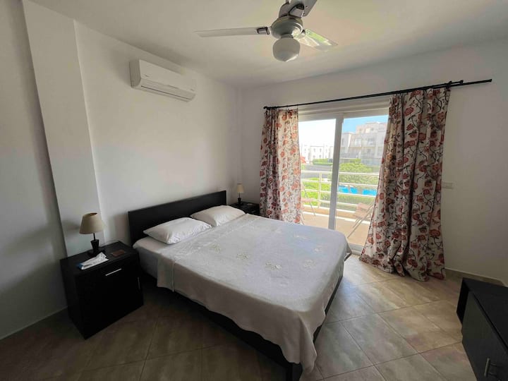 Chambre à l'étage comprenant un lit double ainsi qu'une petite terrasse donnant sur un espace paysager donnant sur un espace paysager comprenant une piscine