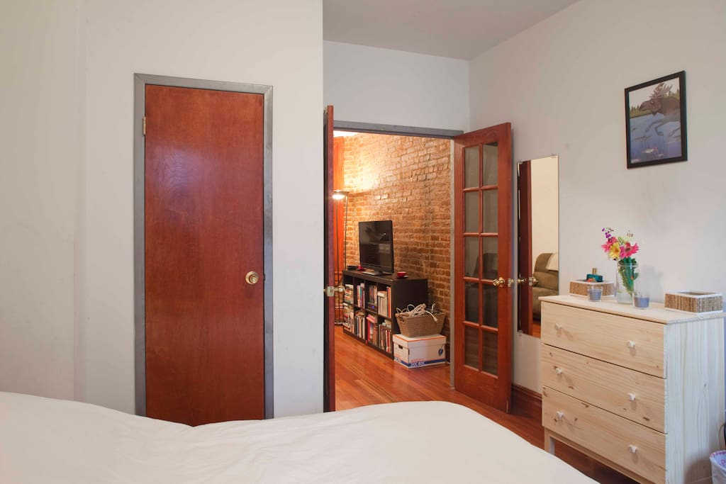 Bedroom has french doors, closet, and dresser.