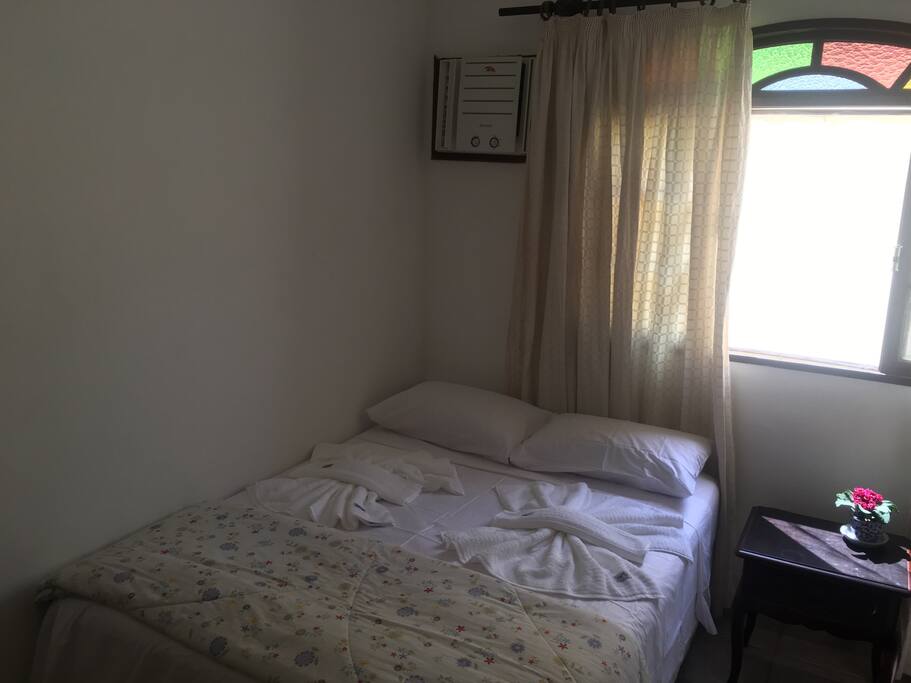 Quarto com cama de casal, armário, ar condicionado e ventilador de teto.