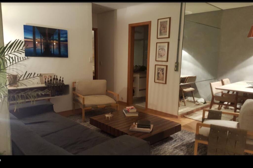 sala com sofa poltronas televisao ao fundo porta do banheiro a ser locado