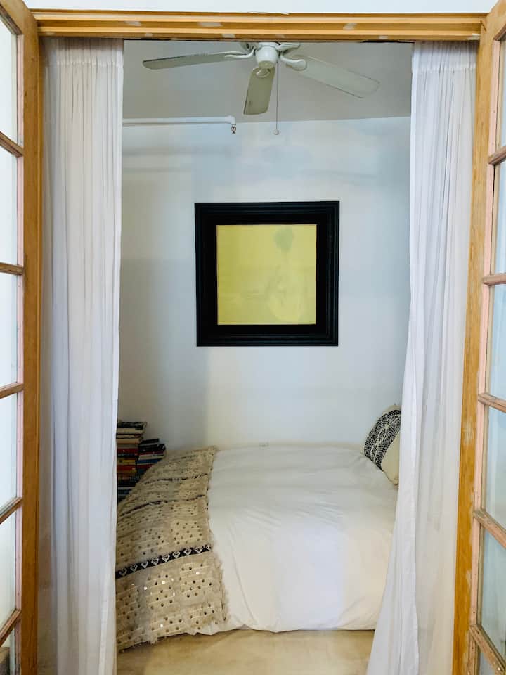 El acogedor dormitorio tiene una cama tamaño queen con pantallas chinas antiguas utilizadas como cabecera.