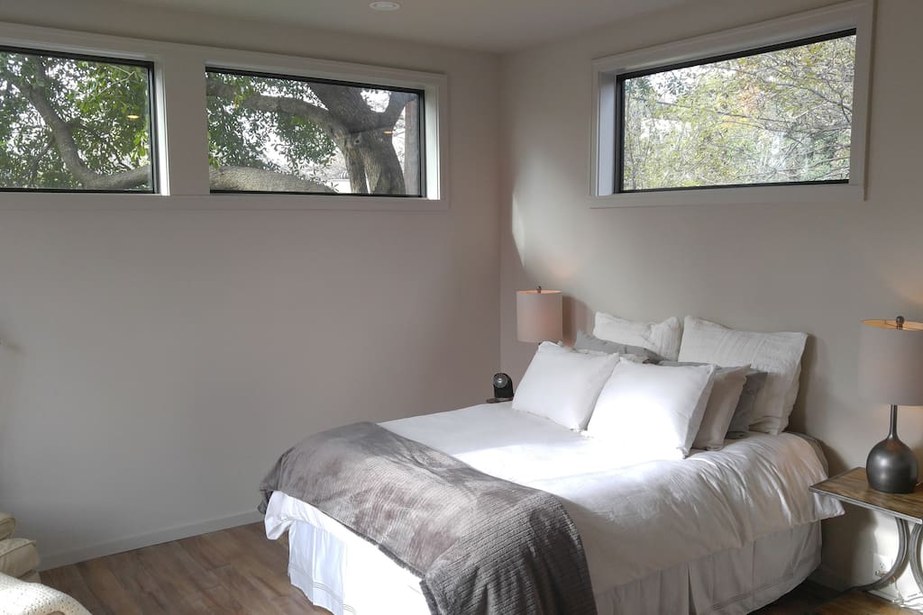 Inside the bedroom at the back of the guest house, you'll find a Queen size bed with high windows, lots of privacy while providing a connection to the trees outside.