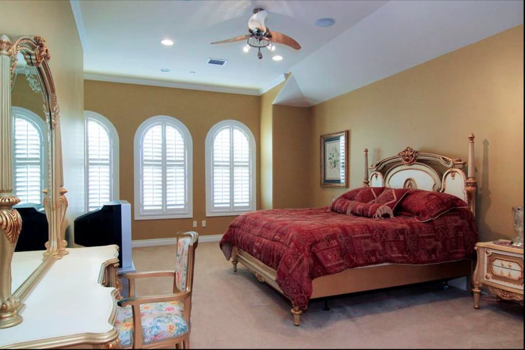 another guest suite with arched windows, ceiling fan, carpet and private bath.