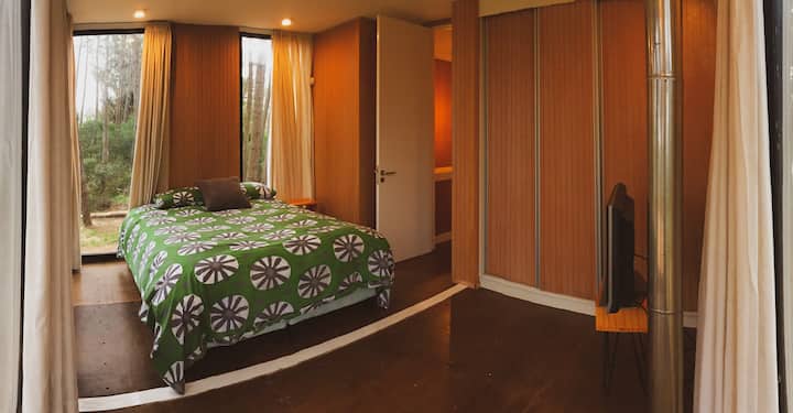 Hlavná spálňa s manželskou posteľou. Veľké okná a terasa s výhľadom na les a oceán. Skvelý výhľad na západ slnka. Spálňa má televízor.