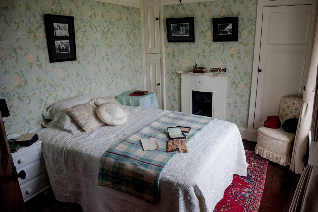 Bedroom with double bed, original fire place, wooden floors and Persian rug.