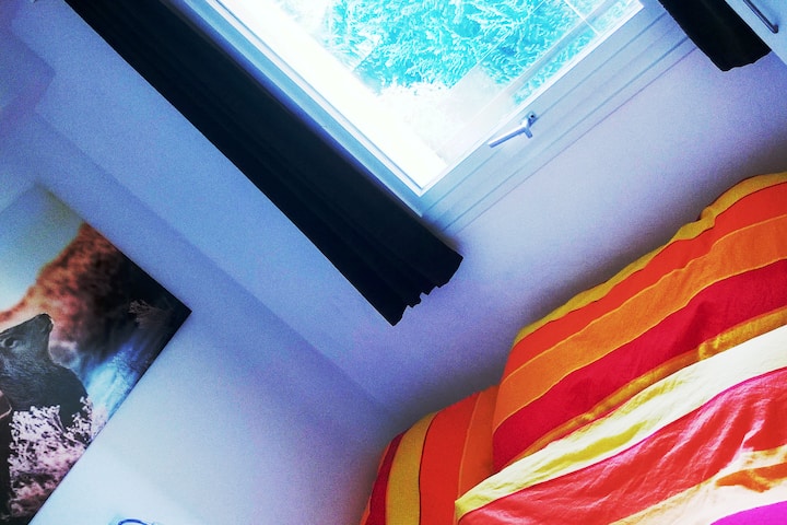 Мала спална соба со двоен кревет, гардероба и мал телевизор.