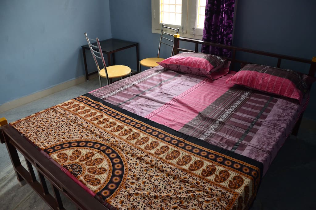 Bedroom consists of a Double bed, a fan and two chairs