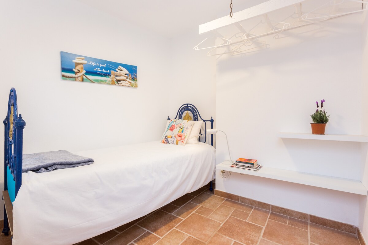 Dormitorio con cama individual, conectado a la casa principal a través de una pequeña terraza.