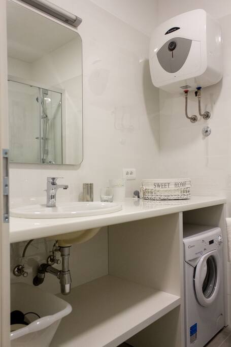 Bathroom with shower, washing machine, hairdryer, hand soap, shower gel, shampoo and clean towels.