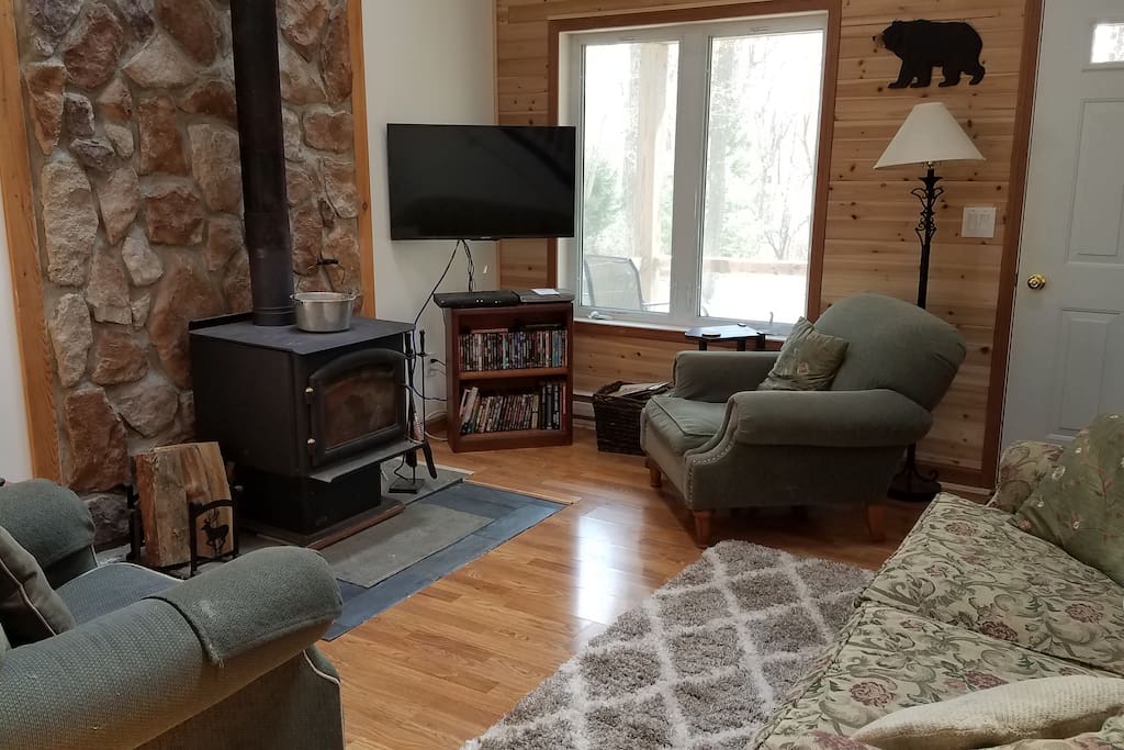 Living room has hardwood floor, full size couch, two chairs, firebox and TV with Dish Network and DVD
