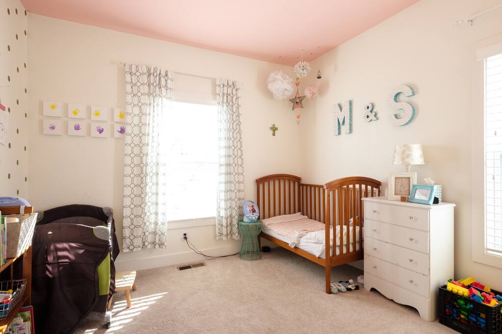 Toddler bed and travel crib in second bedroom. Toys, books, and a changing table.