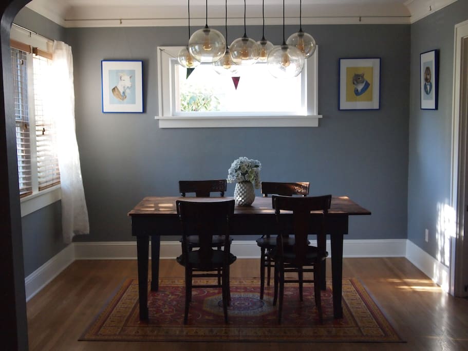 Dining room with local Portland animal art, reclaimed barn wood table, and hand-carved 1910 seats for 4 (less unique IKEA folding chairs for 2 more).
