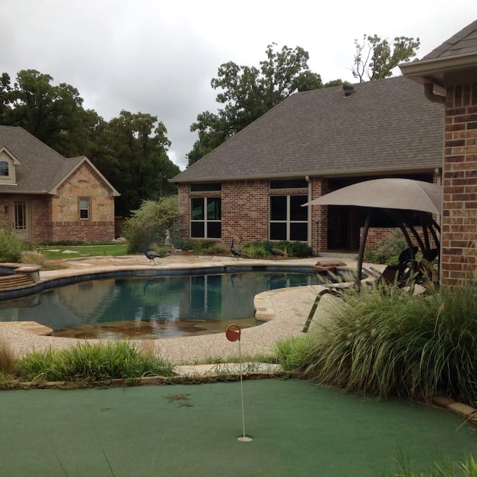 The putting green, pool and game room in front of the guest house.