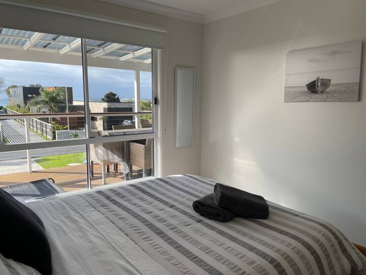 Spavaća soba na katu s bračnim krevetom i pogledom na ocean. 