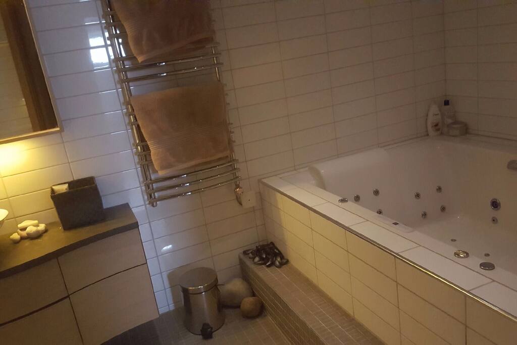 Badrum med handfat och jacuzzi.
Bathroom with a sink and a jacuzzi.