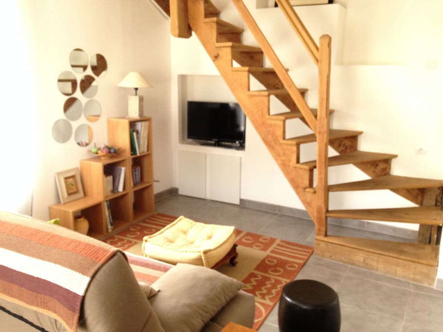 Salon chaleureux avec coin TV et bel escalier en bois montant à la chambre