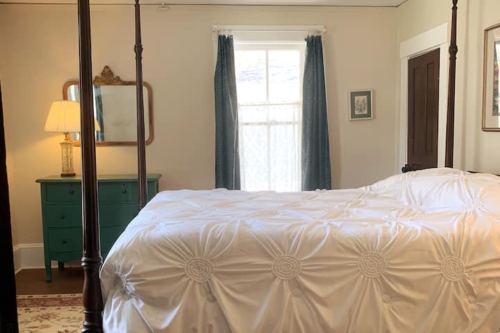 Bedroom 1 has a queen bed and is located toward the front of the house. A window AC unit keeps it cool in the hot months.