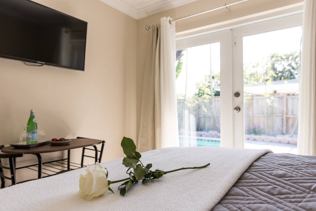 Queen sized bed with cafe table & french doors to the pool