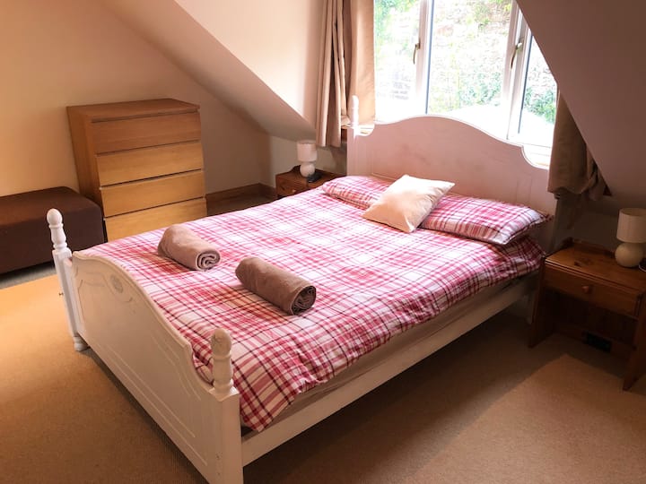 Upstairs master bedroom with a double bed, bedside tables and lamps, chest of drawers, built in wardrobe, large seat, hairdryer and flat screen TV with Sky and an en suite shower room