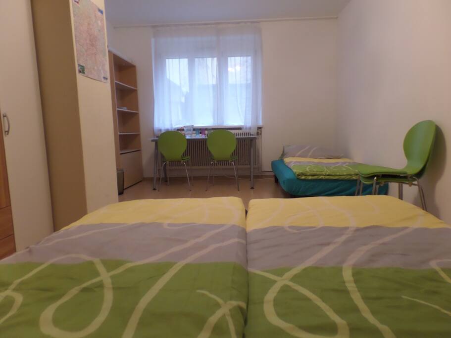 The room is furnished with a queen-size bed, a couch/bed and a table with chairs