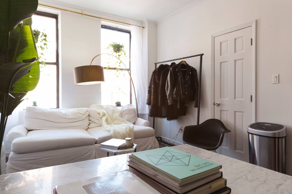 Foliage and designer furniture bring the spacious living room to life. Beautiful white marble table for dining in and a clothing rack (with hangers) for your use. Couch pulls out to a queen bed.