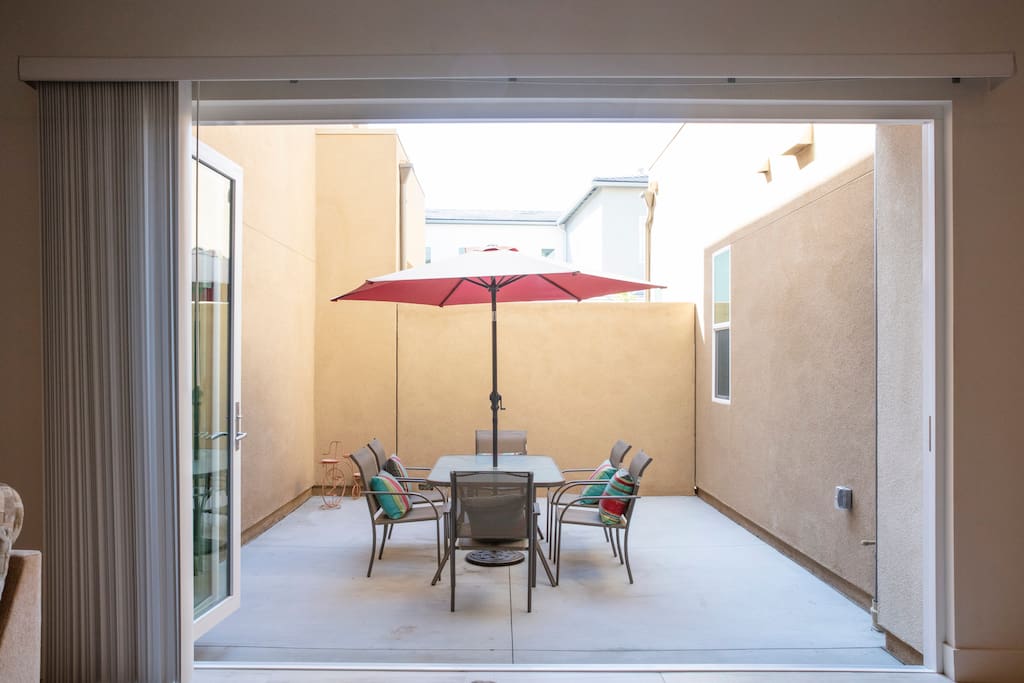 Large private patio features a large umbrella, table, and seating for six.