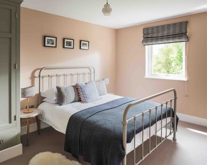 חדר שינה למטה עם נוף לגינה וארון בגדים גדול. 