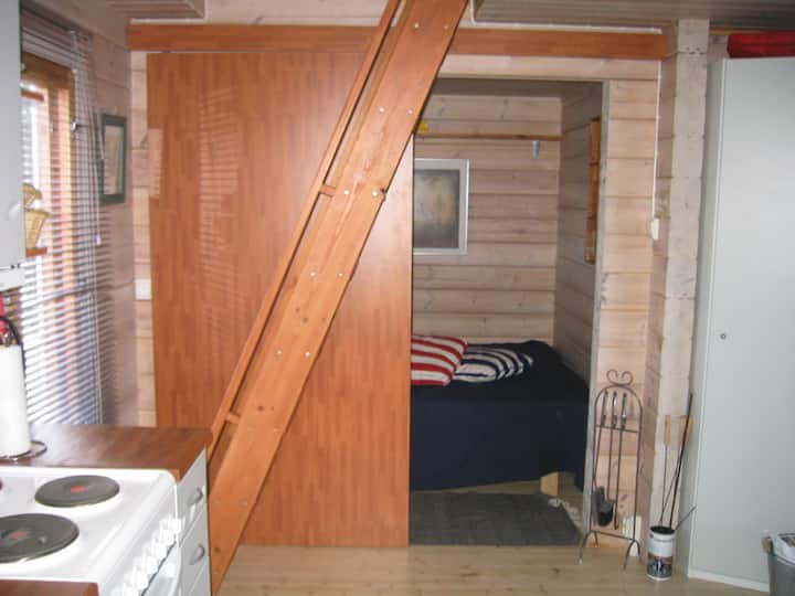 Chumba kimoja kidogo cha kulala kilicho na kitanda cha watu wawili. Vitanda vingine vitatu viko katika eneo la dari lililo wazi.