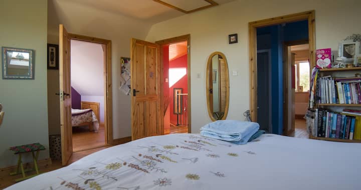 Lit king size avec chambre double attenante à gauche. Salle de bain partagée à droite Hall rose vers les escaliers. La salle de bain est partagée avec les invités à l'étage.